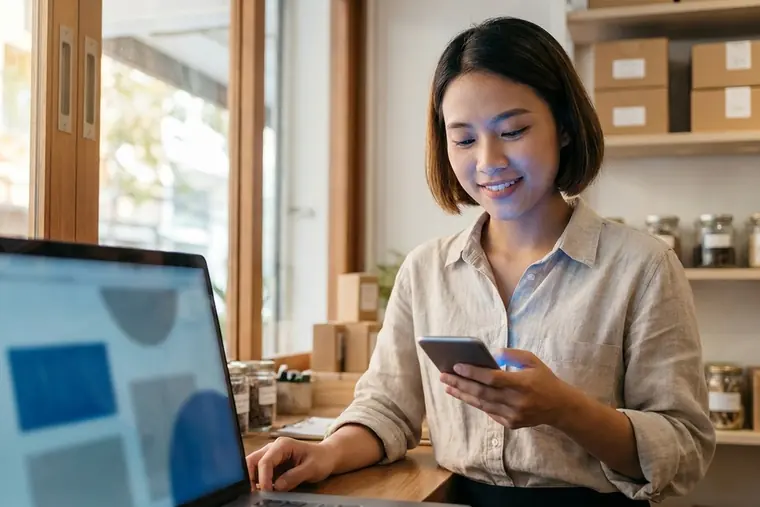 Chủ cửa hàng trả lời tin nhắn khách hàng trên máy tính và điện thoại
